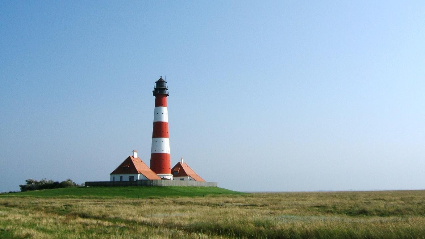 Rot-weißer schleswig-holsteinischer Leuchtturm in Wiesenlandschaft